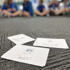 3 cards on carpet with children in background